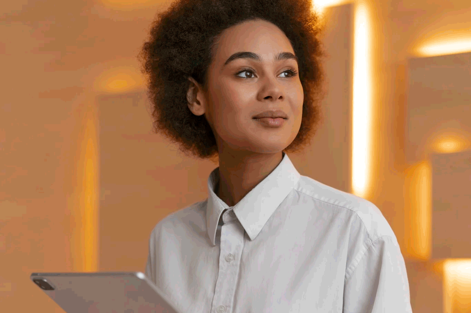 Mulher negra vestida de maneira executiva com um leve sorriso e confiança.