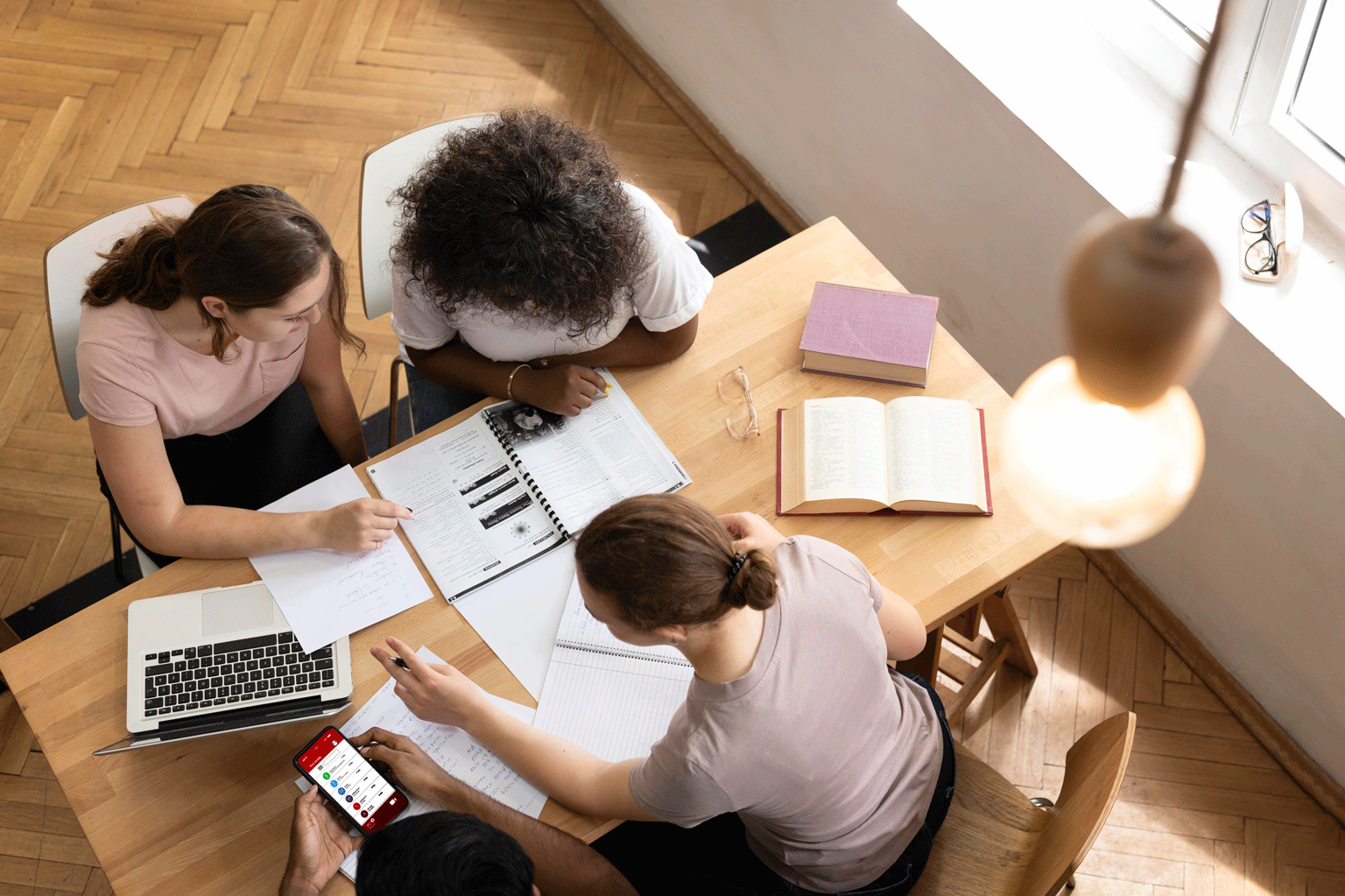 Na imagem tem 5 jovens sentados conversando e estudando