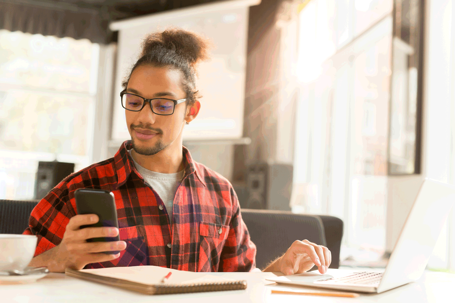 Jovem aprendiz mexendo no celular e estudando.