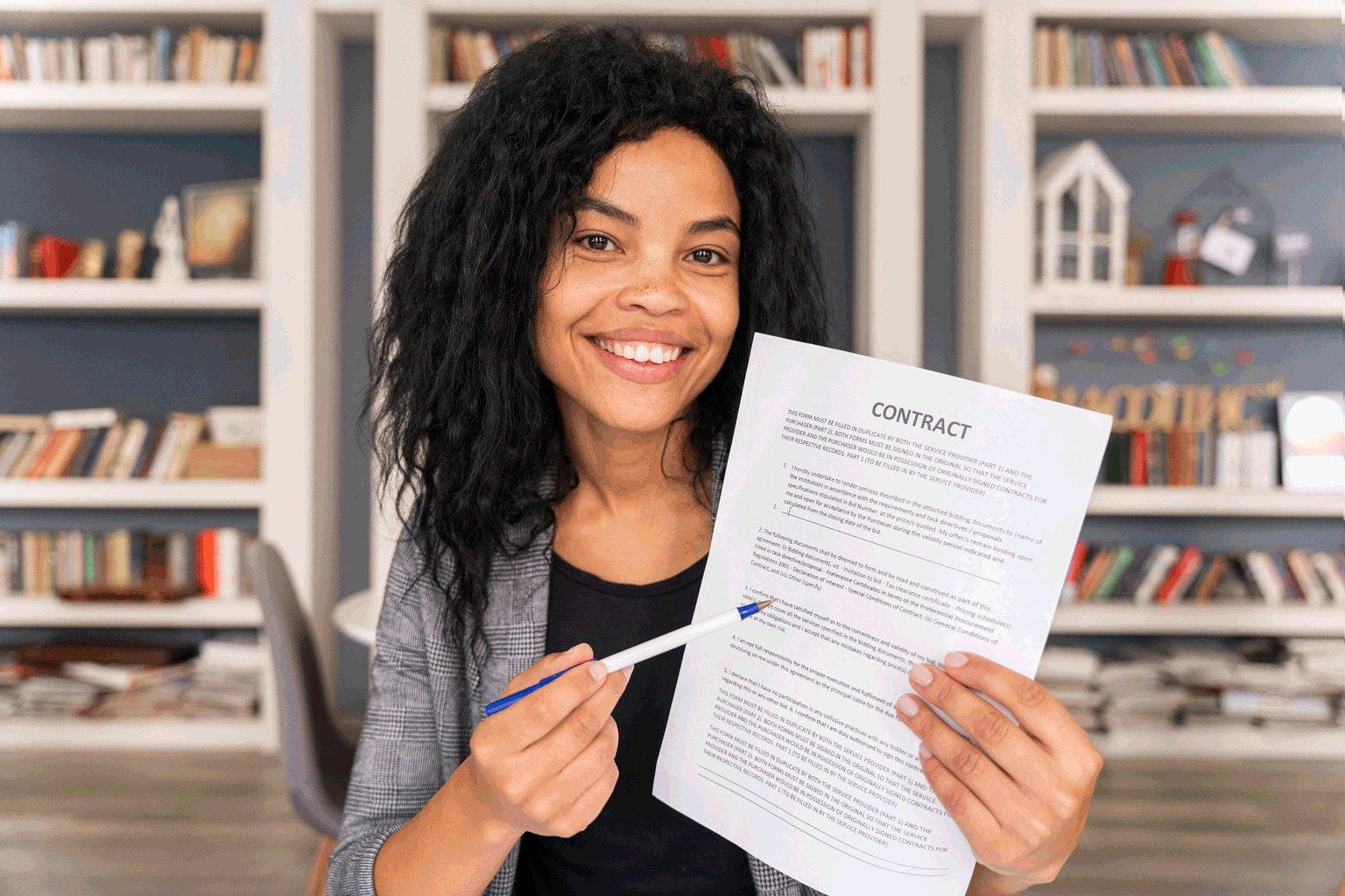 Jovem negra sorrindo segurando um contrato para a matéria sobre: estagiário tem direito a décimo terceiro?