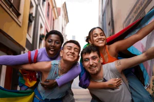 Na imagem 4 jovens, todos pintados com as cores da bandeira lgbt, representando a inclusão de minorias.