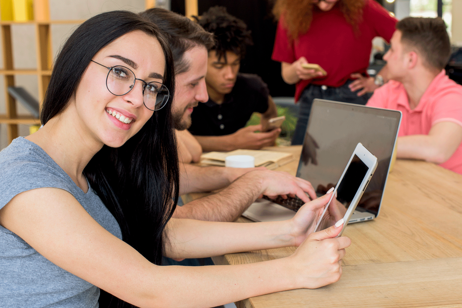 Jovem aprendiz usando tablete e sorrindo, falando sobre a tecnologia.