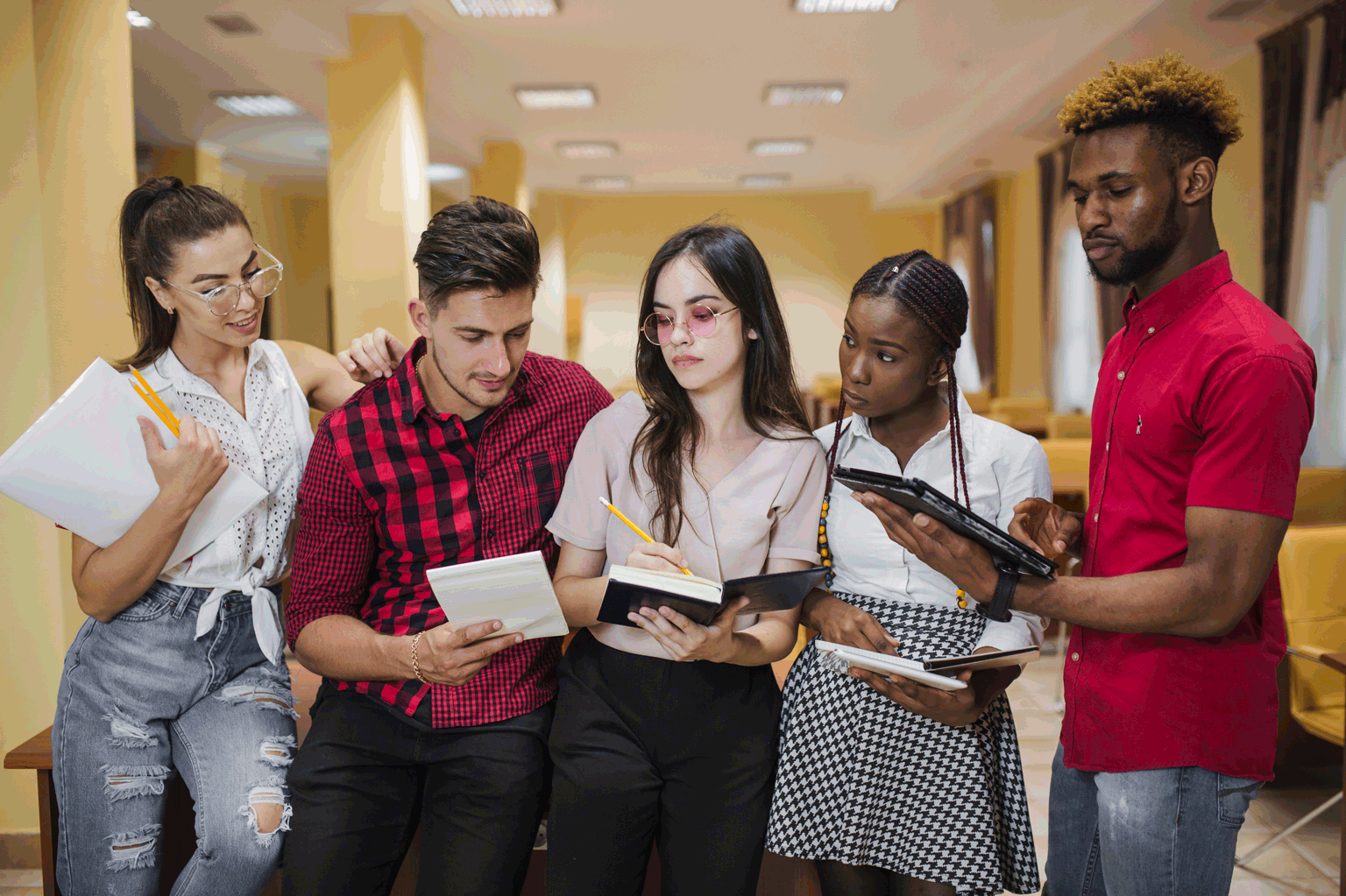 Jovens aprendizes na escola conversando com livros abertos, sem celulares.