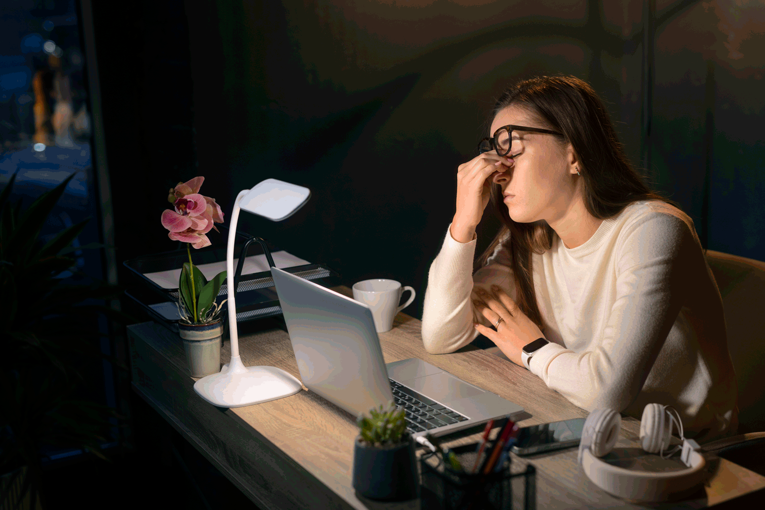 Na imagem uma mulher esfregando os olhos em sinal de cansaço na frente do notebook.