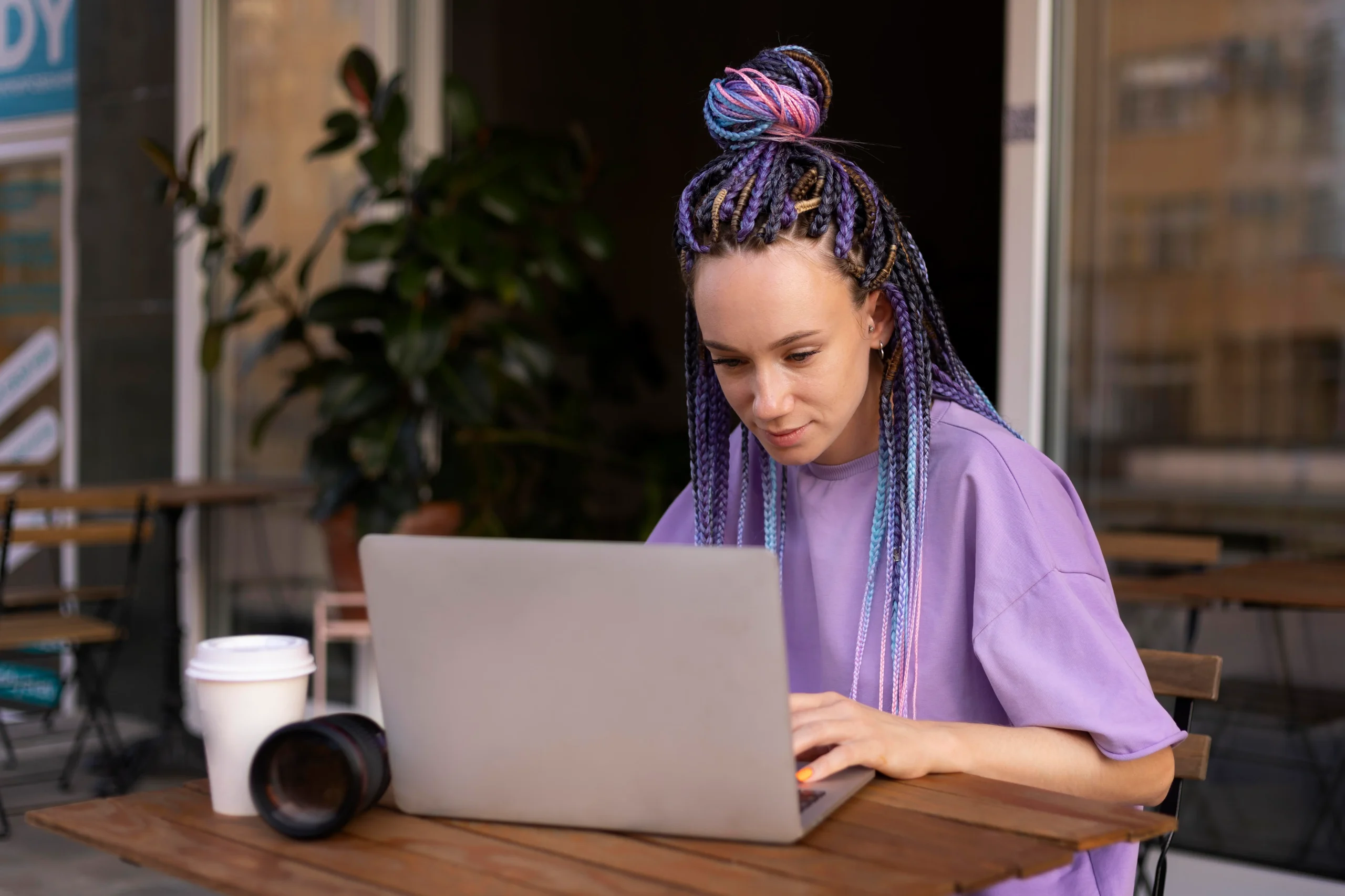 Mulher jovem concentrada trabalhando no computador em casa, representando o modelo híbrido de trabalho remoto e presencial.