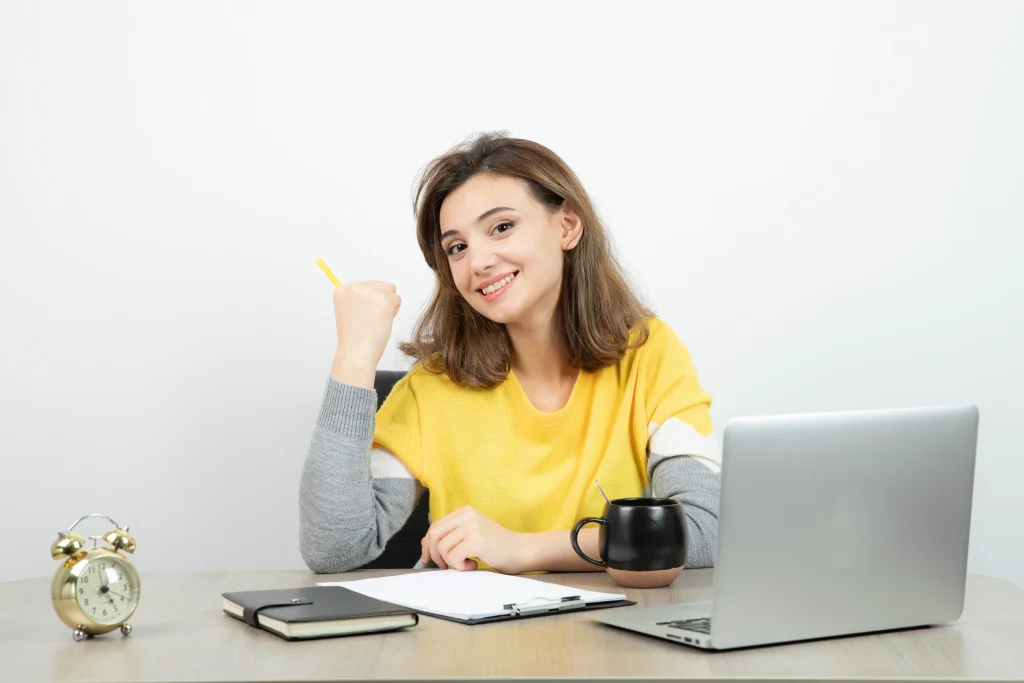 Jovem estagiário sorrindo em frente ao computador, com anotações ao lado.