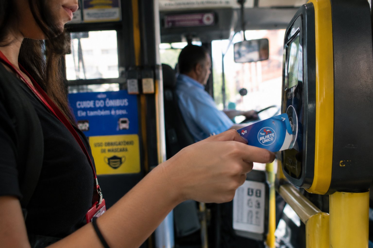 Jovem aprendiz passando o cartão de vale-transporte na catraca do ônibus