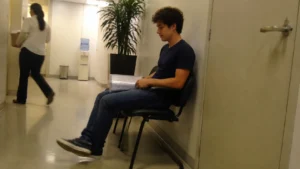 Jovem aguarda sentado no corredor antes de uma entrevista de jovem aprendiz