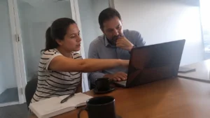 Dois profissionais revisando juntos no notebook a fidelização de clientes corporativos em uma sala de reunião