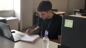 Jovem anotando à mão no caderno a rotina de hábitos que geram resultado no início do dia de trabalho