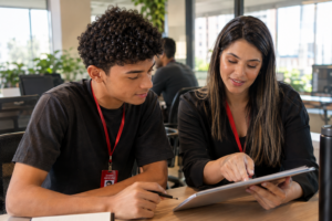Jovem aprendiz recebendo orientação prática de um mentor em ambiente de trabalho