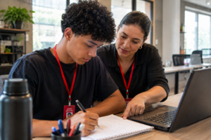 Mentor orientando jovem aprendiz durante atividade de capacitação na empresa
