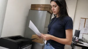 Jovem aprendiz conferindo folhas impressas, parte do investimento em jovem aprendiz e do acompanhamento na empresa