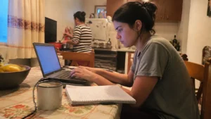 Jovem aprendiz primeiro emprego, jovem atualiza o currículo no notebook na mesa da cozinha