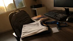 Jovem aprendiz no ensino médio, mochila escolar, uniforme dobrado, caderno e crachá sobre a mesa de trabalho