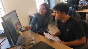 Tutora orientando um jovem aprendiz no monitor, rotina de jovem aprendiz nas empresas