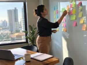 Mentoria eficaz, analista de RH organiza duplas de mentoria com post-its em uma sala de reunião