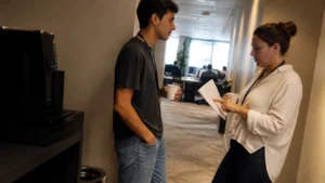 Jovem aprendiz conversando com uma colega de outra área no corredor, um exemplo de networking para jovens