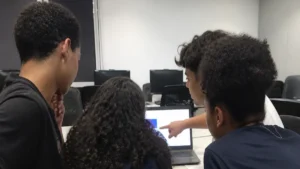 Como descobrir seu talento, jovens aprendizes reunidos em volta de um notebook no escritório
